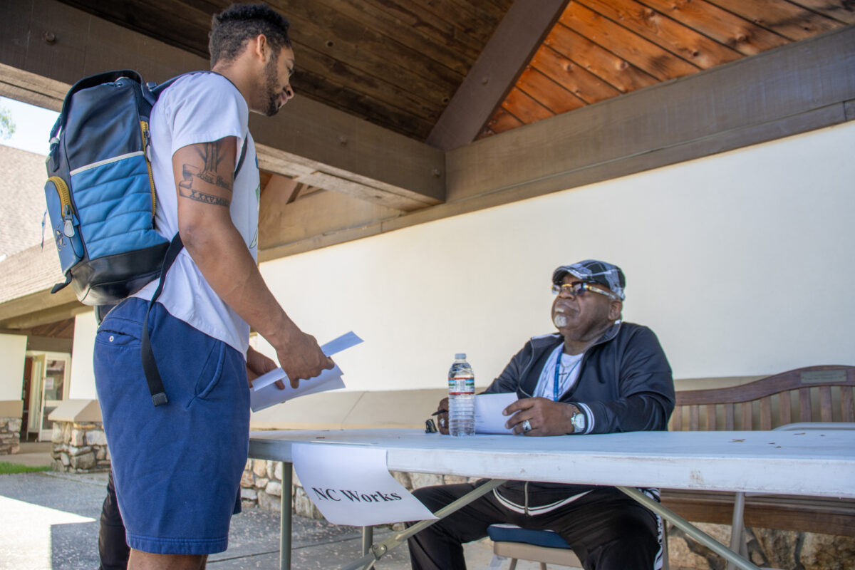 A student chats with a man representing NC Works at a table outside the chapel.