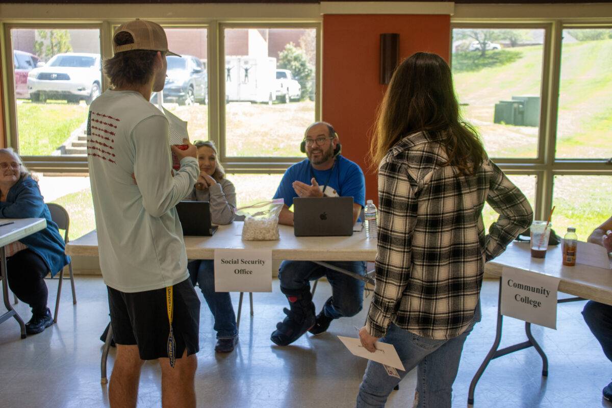 Two students talk with representatives from agencies at a table in the fellowship hall.