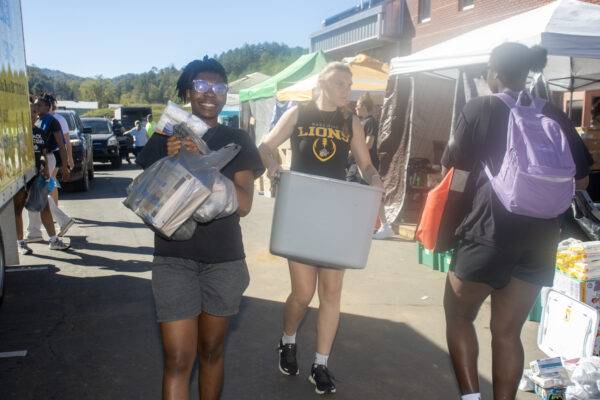 Students carry bags and boxes of relief supplies.