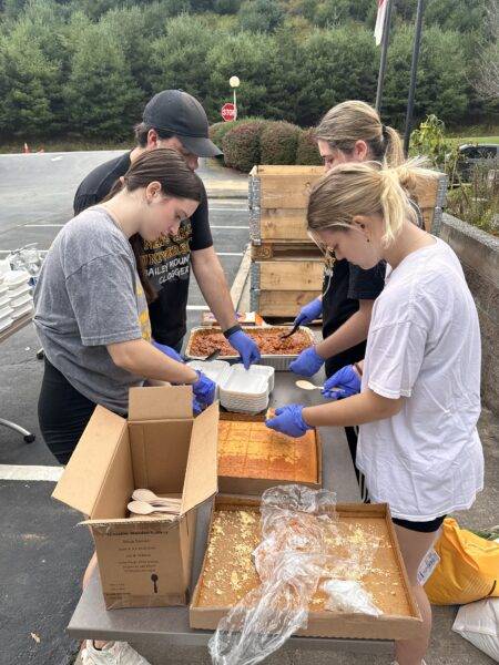 Students set up a food service line in a parking lot.