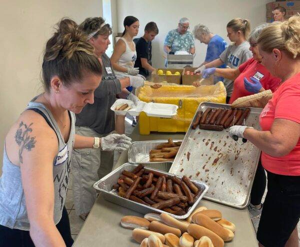 Students and other volunteers prepare hot dogs and other food at a relief site.