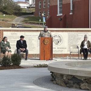 Gerry, alumni board president, speaks behind the lectern in front of the Founders Memorial.