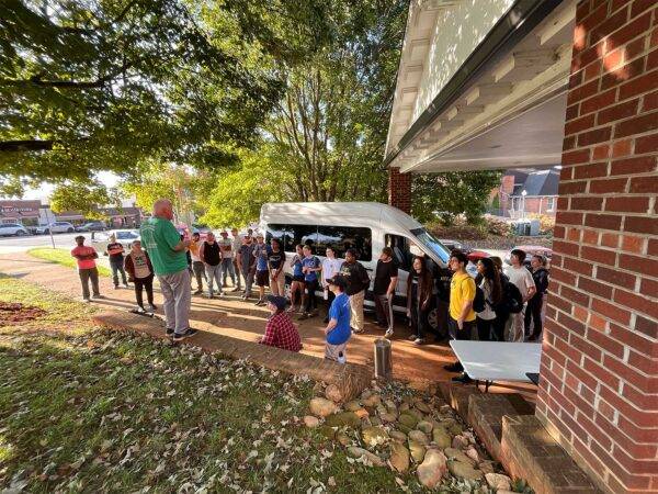 Students gather next to a van while Rev. Tommy Justus gives instructions for their service project.